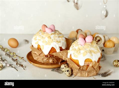 Easter Cakes With Painted Eggs Feathers And Pussy Willow Branches On Table Near White Wall