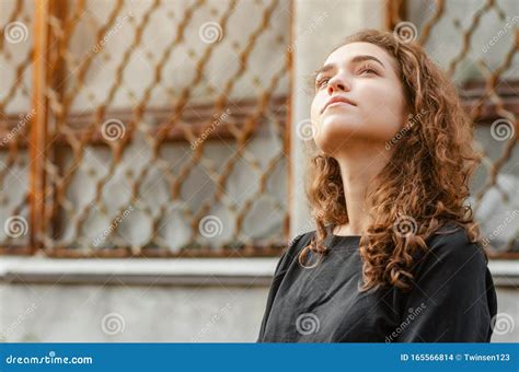 Portrait Nice Girl With Curly Hair In Dark Jacket On Background Of Abandoned Industrial Building