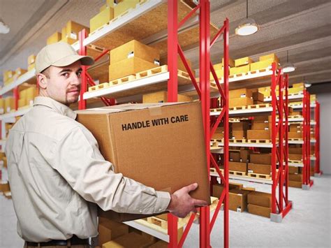 Premium Photo Portrait Of Delivery Man Holding Box In Warehouse