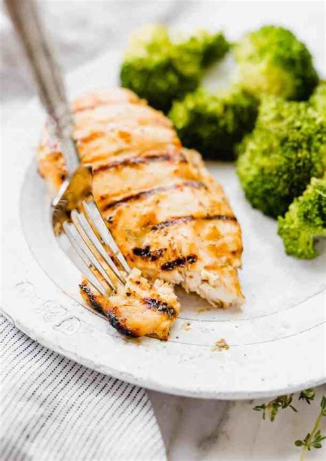 A White Plate Topped With Chicken And Broccoli Next To A Knife And Fork