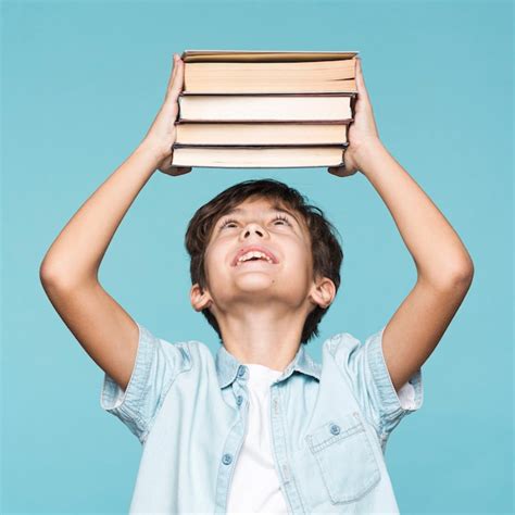 Улыбающийся мальчик держит стопку книг | Бесплатно Фото