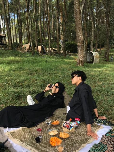 Two People Are Sitting On A Blanket In The Woods And One Person Is