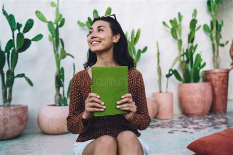 Smiling Young Asian Woman Enjoying Interesting Book On Veranda Stock