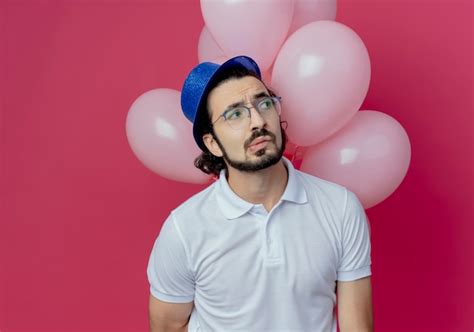 Mirando Al Lado Confundido Guapo Con Gafas Y Sombrero Azul De Pie