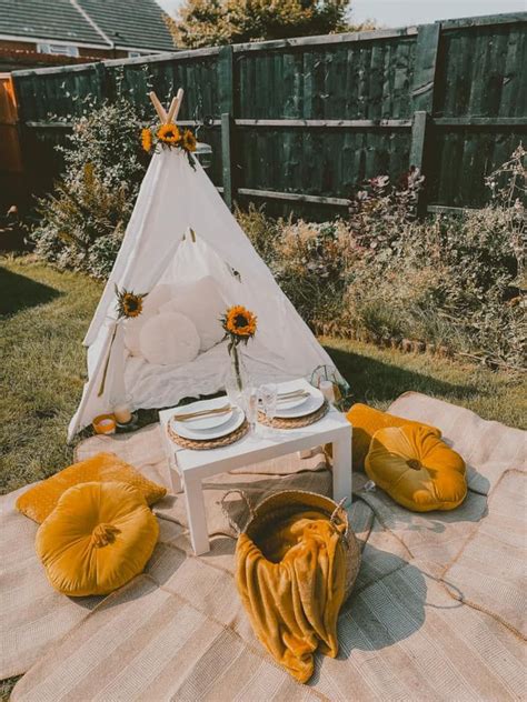 A Teepee Tent Set Up In The Backyard With Sunflowers And Plates On It