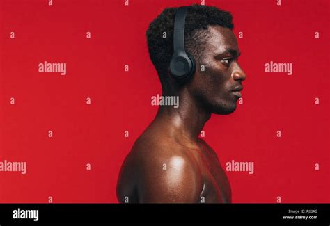 Side View Of Shirtless African American Man With Headphone On Red Background Fit Man Listening