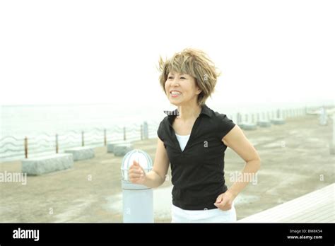 Mature Woman Jogging On Beach Smiling Stock Photo Alamy