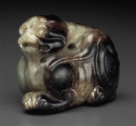 A SMALL GREENISH GREY AND DARK BROWN JADE FIGURE OF A MYTHICAL BEAST