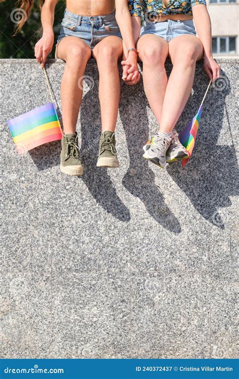 Pareja Lesbiana Irreconocible Sentada Con La Mano Con Banderas De Arco Iris Imagen De Archivo