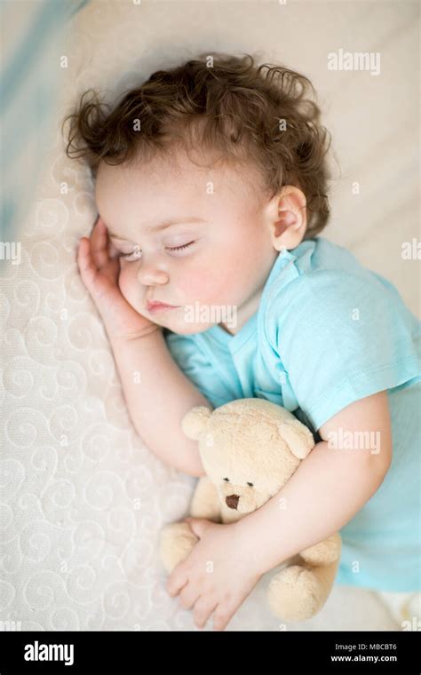 Sleeping child in bed, holding a teddy bear Stock Photo - Alamy