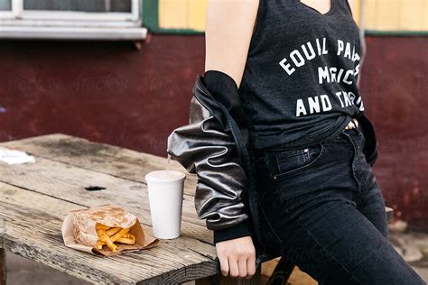 Young Woman Eating Fast Food French Fries And Soda Outside Diner On Bench By Stocksy