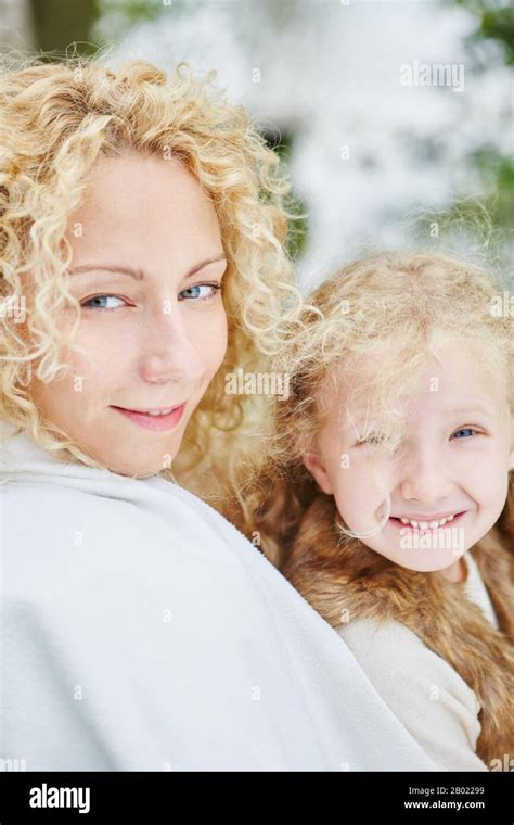 Mother And Daughter With Blonde Curly Hair Look At Camera Together Stock Photo Alamy