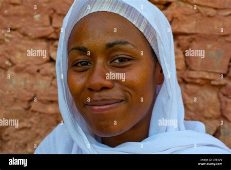 Portrait of a smiling, dark-skinned, young woman wearing a white ...