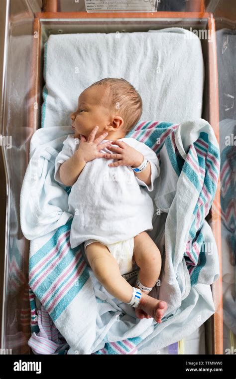 Newborn Baby Wearing Striped Hat In A Hospital Bassinet Stock Photo