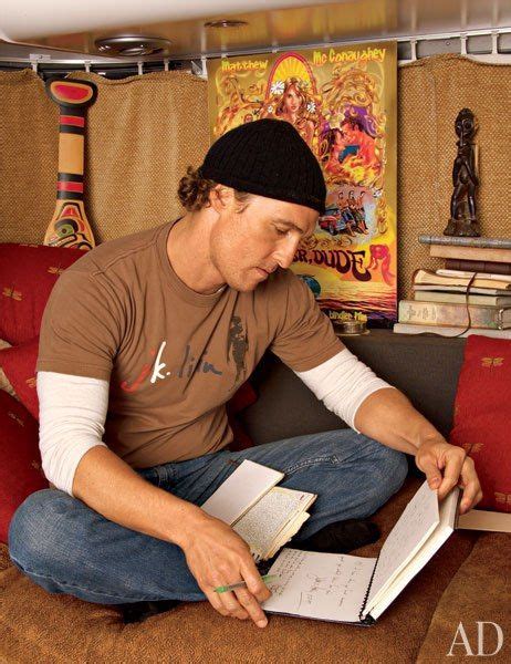 A Man Sitting On Top Of A Brown Couch Holding An Open Book In His Hands