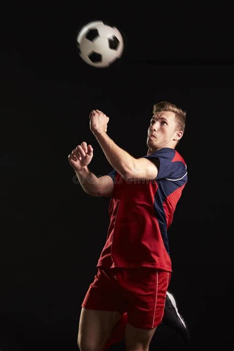 Professional Soccer Player Jumping To Head Ball In Studio Stock Photo