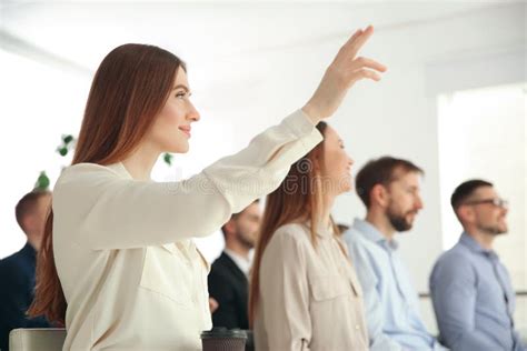 Young Woman Raising Hand To Ask Question At Business Training Stock