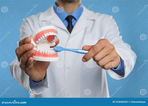 Dentist With Jaws Model And Toothbrush On Light Blue Background