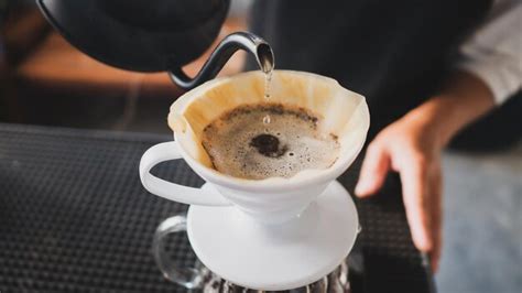 Hand gotejamento coffee barista derramando água quente no café torrado