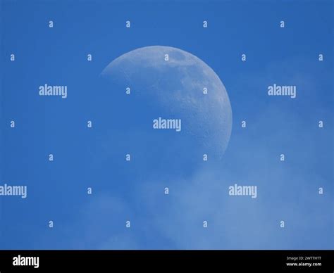 Half Moon Shining In Sky With Clouds And Blue Background Stock Photo