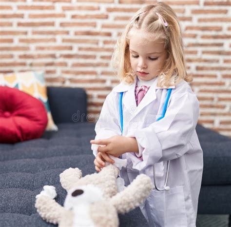 Adorable Blonde Girl Preschool Student Sitting On Sofa Drawing On Notebook At Home Stock Photo