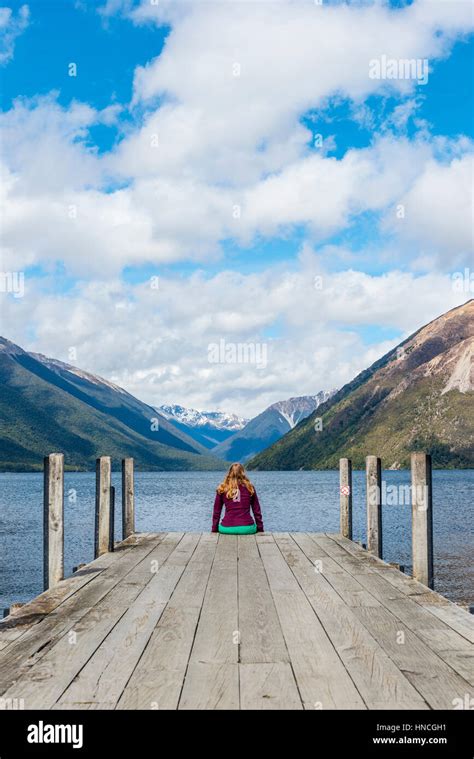 Woman Sitting On Dock View Of Lake Rotoiti Nelson Lakes National Park