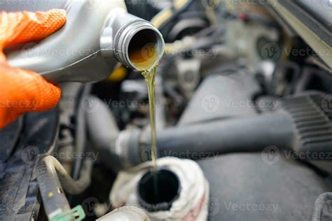 Gießen Öl zu das Wagen Auto Mechaniker halten ein Flasche von Öl im