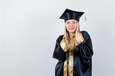 Fille Blonde Serrant Les Poings En Robe De Graduation Et Casquette Et L Air Heureux Photo Gratuite