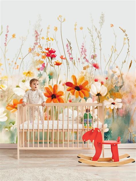 a baby sitting in a crib next to a flower mural