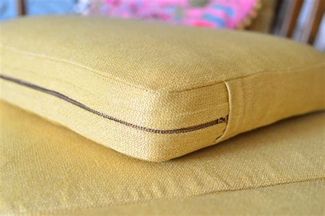 A Close Up Of A Yellow Pillow On A Chair With A Pink Cushion Behind It