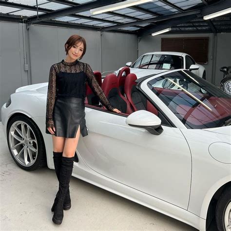 A Woman Standing Next To A White Sports Car In A Garage With Its Doors Open