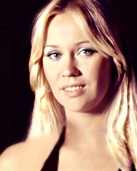 A Woman With Long Blonde Hair And Blue Eyes Posing For A Photo In Front