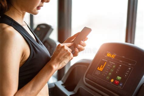 Woman Using Smart Phone When Workout Or Strength Training At Fitness Gym On Treadmill Relax And