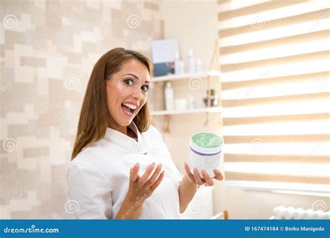 Una Bella Joven Enfermera De Brunette Se Ríe Y Mira La Cámara Mientras Tiene En Sus Manos Un Gel