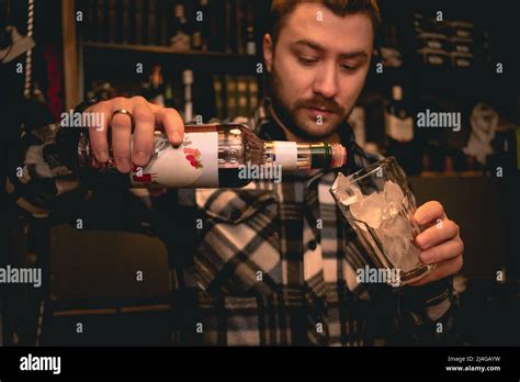 Bartender Pouring Grenadine Syrup From Bottle Into Glass With Ice