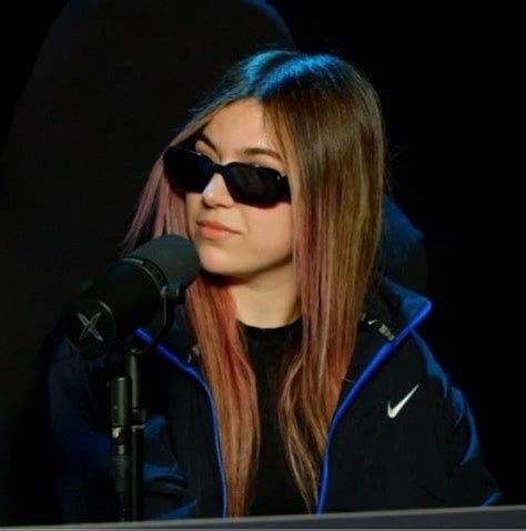 A Woman With Sunglasses On Sitting In Front Of A Microphone