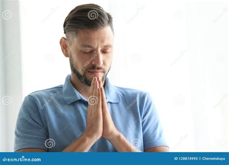 Man With Hands Clasped Together For Prayer On Light Background Stock