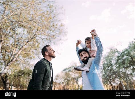 Couple gay avec leur petite fille dans le parc Le père tient la fille sur ses épaules dans une