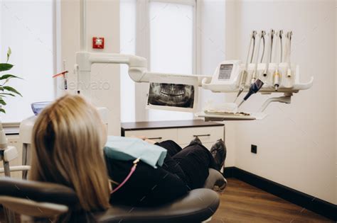 Patient Sitting On Dental Chair Wearing Dental Bib Waiting For Her