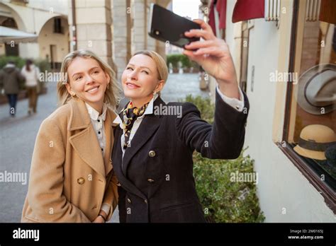 Lächelnde elegante reife blonde Frau sich selbst und eine wunderschöne junge Dame vor den