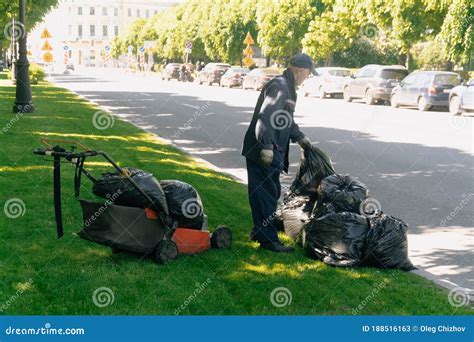 Un Hombre Recoge Basura En Bolsas En La Acera El Concepto De Limpieza