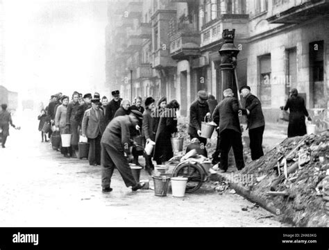 Berliner Line Up For Water Berliners Stand In Front Of A Water Pump On