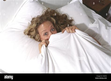 Female Long Wavy Blonde Hair Lying In Bed Covered White Sheet Pulled Up