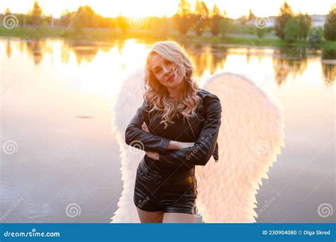 Blonde Woman In Black Leather Jacket And Shorts With White Angel Wings