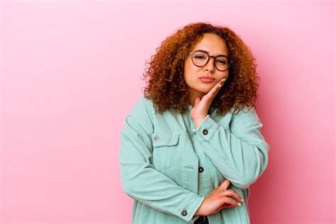 Jovem latina curvilínea isolada na parede rosa que se sente triste e pensativa olhando para o