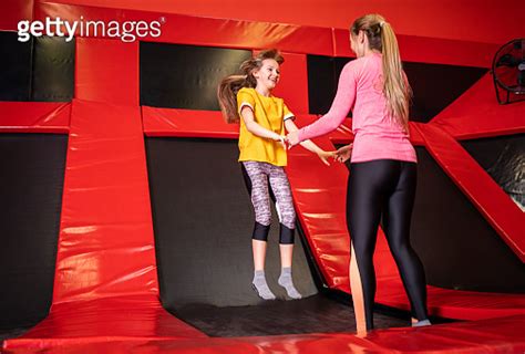 Happy Mother And Daughter Jumping On Trampoline In Fintess Center 이미지