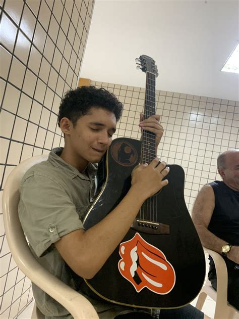 A Man Sitting In A Chair Holding An Acoustic Guitar