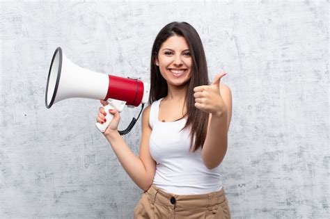 Premium Photo Young Pretty Woman Holding A Megaphone Against Cement Wall