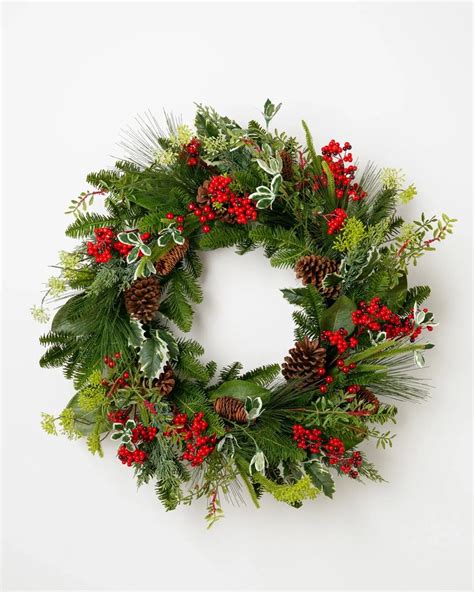 A Christmas Wreath With Red Berries Pine Cones And Greenery