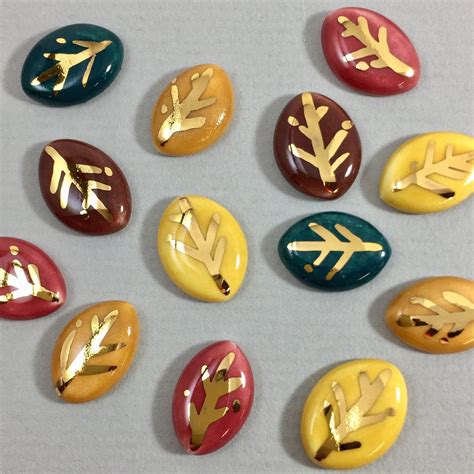 Several Different Colored Stones With Gold Leaf Designs On Them All In